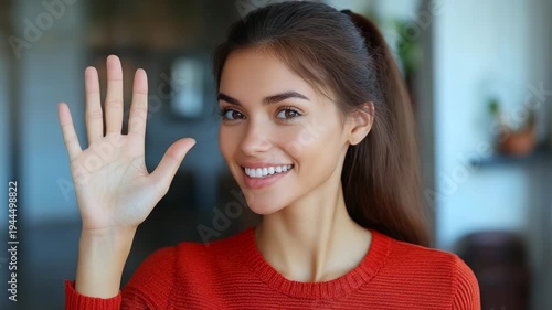 Wallpaper Mural Smiling young woman with hand raised, wearing a red sweater. Brown hair and eyes, indoors Torontodigital.ca