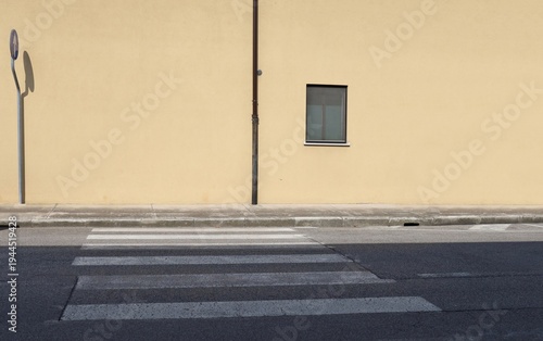 Wallpaper Mural Yellow plaster wall with a window and gutter in the middle and road sign on the left. Concrete sidewalk, crosswalk and street in front. background for copy space. Torontodigital.ca