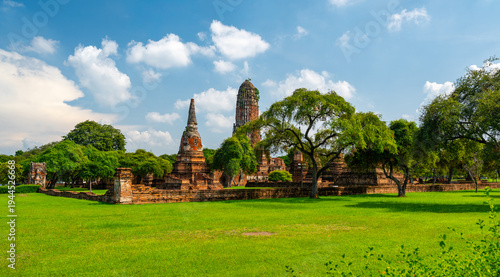 Ancient stupa towers in Ayutthaya historical park, Thailand. Ruins of former Siam capital under blue sky on sunny day. Famous travel destination with cultural heritage and Buddhist history.