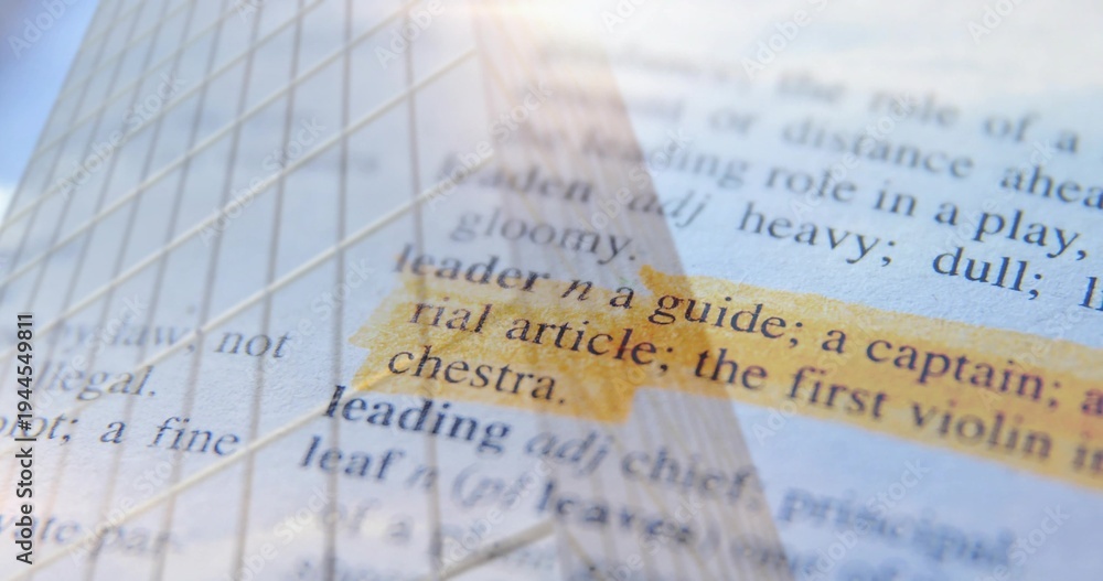 Fototapeta premium Showing highlighted dictionary entry 'leader' reflecting skyscraper facade over desk surface