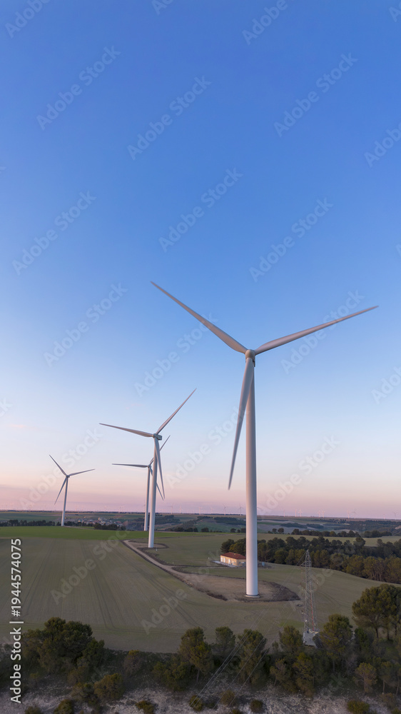 Obraz premium Wind turbines on hill producing renewable energy in countryside landscape