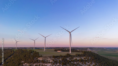 Wind turbines on hill producing renewable energy in countryside landscape