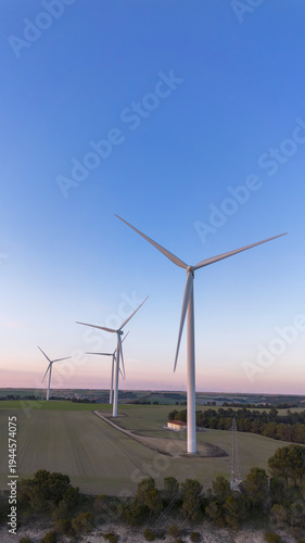 Wind turbines on hill producing renewable energy in countryside landscape