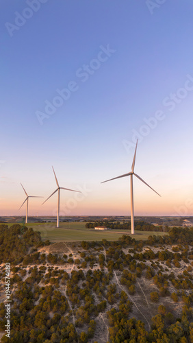 Wind turbines on hill producing renewable energy in countryside landscape
