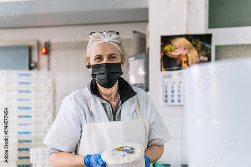 Senior food worker making cheese wearing mask and hairnet