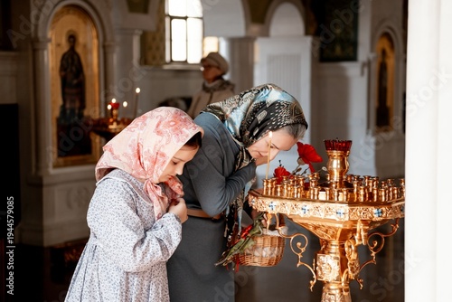 Slika na platnu mom and daughter put candles and pray in the Orthodox church, congratulating eac