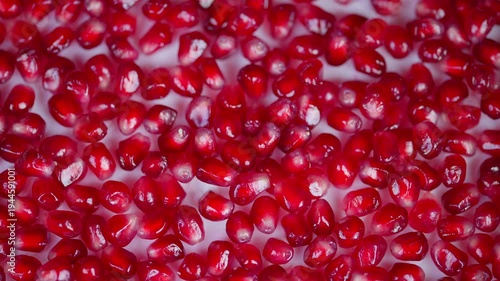 Juicy pomegranate seeds closeup shot. Reflective surface showcases vibrant seed clusters. Cinematic style focusing on fresh pomegranate seeds shimmering under bright light