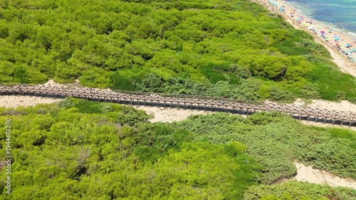 Aerial drone flight above Mediterranean coastal vegetation and beach path Mallorca Spain