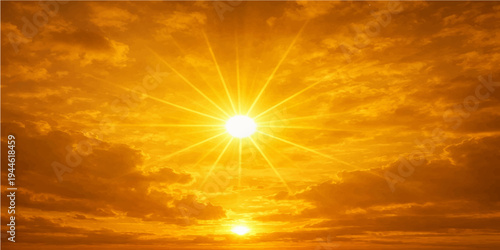 Beautiful summer landscape of a bright yellow sun in a blue sky with soft white clouds at sunrise creating a beautiful orange and red nature cloudscape