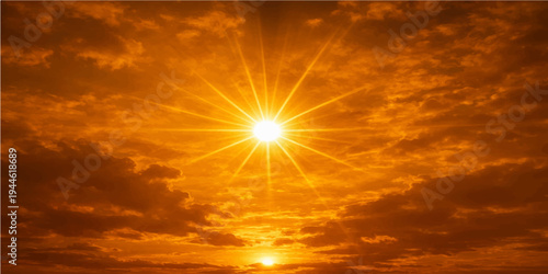 A beautiful summer cloudscape at sunset features the dramatic sun in a blue and orange sky with pink clouds during a golden nature dusk