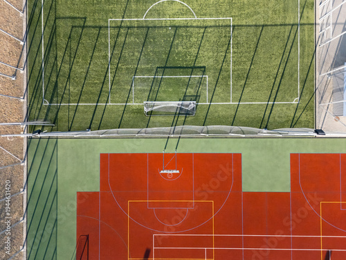 Foto Symmetrical red and green multi sport court with long shadows, aerial view