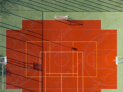 Red and green multi sport court with layered markings and shadows, aerial view
