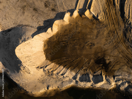 Sandy excavation crater with radial erosion pattern, aerial drone view