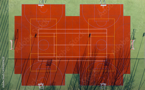 Red and green multi sport court with line markings and shadows, aerial top view