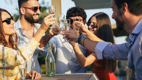 Foto Friends clinking champagne glasses in celebratory toast at sunset rooftop party