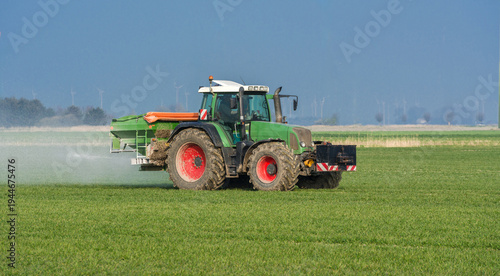 Tractor spreading fertilizer in spring on a grain field 