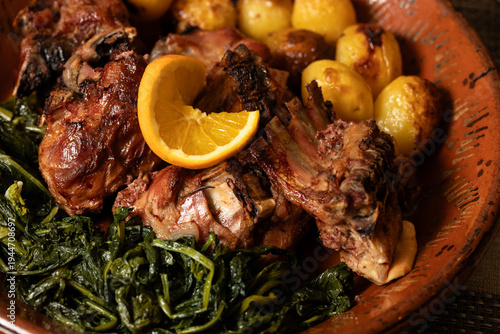 Roast kid goat, a traditional dish from northern Portugal, served with golden potatoes, sautéed greens, and a fresh orange slice, highlighting rustic flavors and hearty regional cuisine.