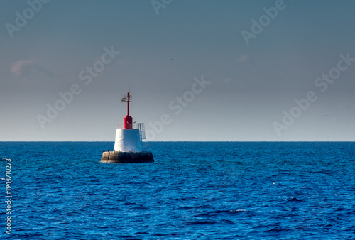 isolated red and white navigational buoy floating in the blue adriatic sea