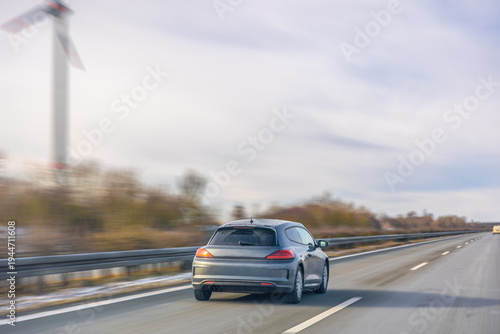 Grey hatchback driving on winter highway. Compact car in motion.