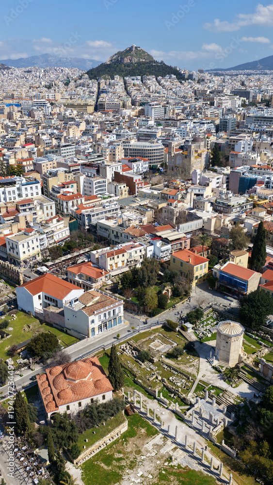 Naklejka premium Aerial drone portrait photo of ancient Roman Market featuring tower of Winds and Gate of Athena in the heart of Athens historic centre built in Plaka district, below Acropolis hill, Attica, Greece