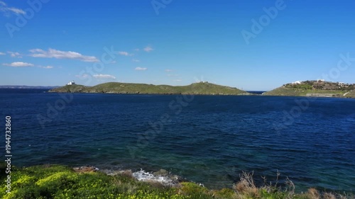 Wide view of Korissia Bay on Kea Island in the Cyclades, Greece, with the lighthouse visible on the headland and wind driven waves across the Aegean Sea, filmed in late winter to early spring with nat