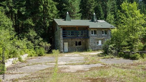 Foto Rustic stone house in a lush forest setting