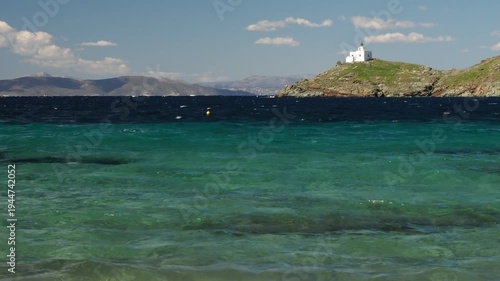 Wide view of Korissia Bay on Kea Island in the Cyclades, Greece, with the lighthouse visible on the headland and wind driven waves across the Aegean Sea, filmed in late winter to early spring with nat