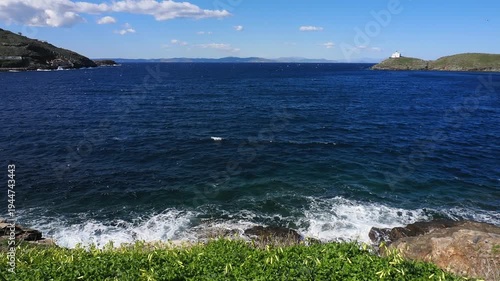Wide view of Korissia Bay on Kea Island in the Cyclades, Greece, with the lighthouse visible on the headland and wind driven waves across the Aegean Sea, filmed in late winter to early spring with nat