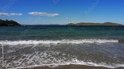 Wide view of Korissia Bay on Kea Island in the Cyclades, Greece, with the lighthouse visible on the headland and wind driven waves across the Aegean Sea, filmed in late winter to early spring with nat