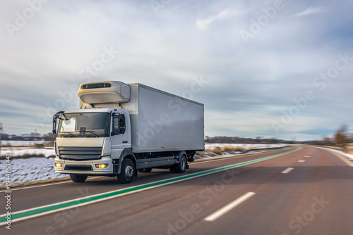 Canvastavla White refrigerated truck transporting cargo on winter highway