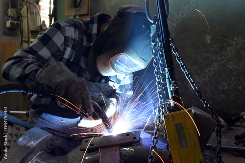 Welder in protective clothing at the workplace in an industrial company in steel construction