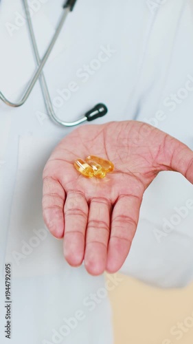 Doctor cardiologist man show lot of tablet pills vitamin D or omega-3 yellow capsules in hand palm, recommends drugs immunization cure treatment. Health care. Apothecary pharmacist on beige background