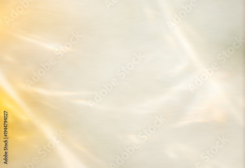 Soft warm golden sunlight reflections on neutral textured background