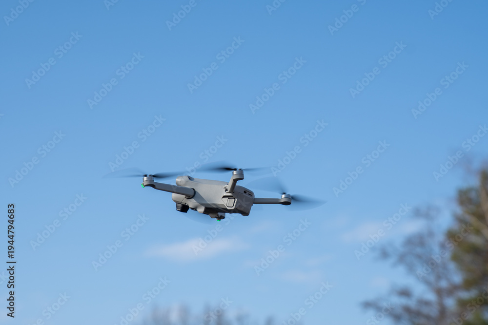 Fototapeta premium flying drone in the sky, sideview, trees in the background
