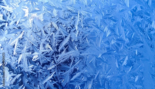 Close-up of blue frosty glass covered with sharp, sparkling ice crystal patterns. 