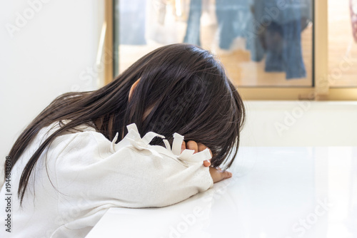 テーブルで腕をマクラにして寝る女の子（5歳、日本人、長髪）