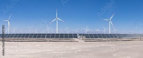 Panoramic view of hybrid plant with solar panels and wind turbines in Atacama Desert, Chile. Solar energy farm with photovoltaic panels and wind turbines under clear blue sky in arid desert landscape