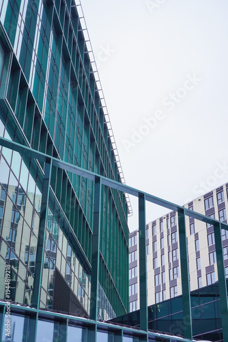 Modern buildings reflect light on a cloudy day in a city area with a unique architectural design
