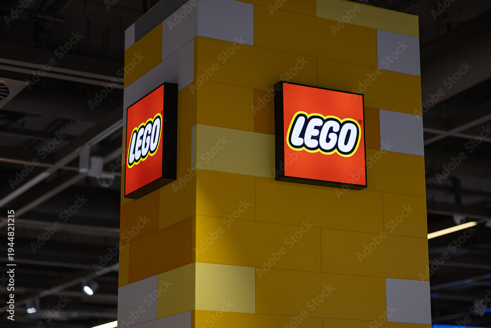 Obraz premium Wroclaw, Poland- October 25, 2025: Lego store logo and illuminated brand signage mounted on a yellow brick patterned column inside a modern retail shopping mall for family entertainment