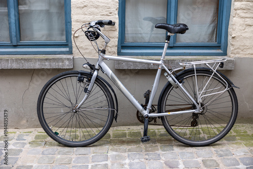 Silver bicycle parked on cobblestone street in bruges
