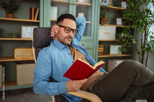 Fotografie Man relaxing at home enjoying leisure reading a book