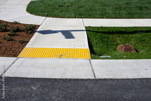 Obraz na plátně Freshly installed concrete sidewalk, yellow ADA Curb Ramp, and landscaping in ne