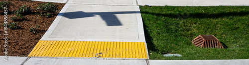 Fotografía Freshly installed concrete sidewalk, yellow ADA Curb Ramp, and landscaping in ne