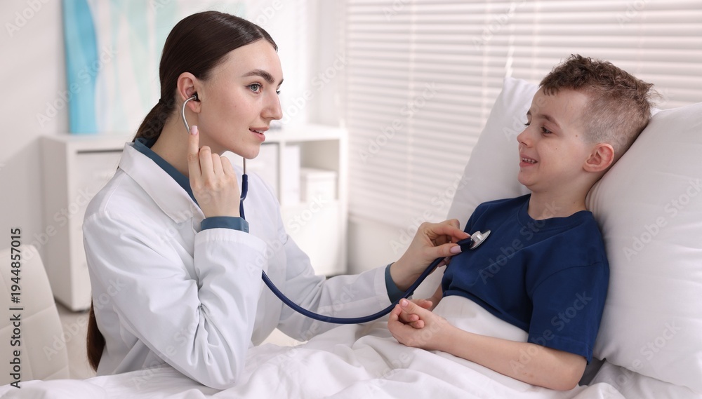 Fototapeta premium Doctor examining little child with stethoscope in hospital