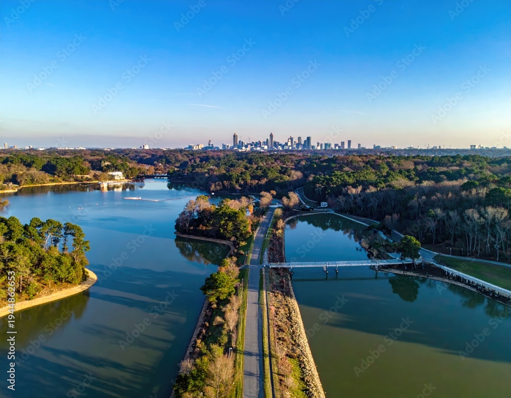 Fototapeta premium Aerial view of a lake and a dam road with a distant city skyline under blue sky