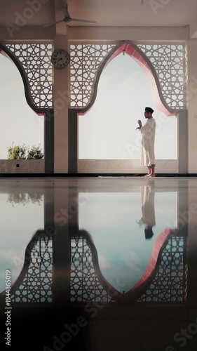 A Muslim man performing Islamic pray inside a mosque during Ramadan, a peaceful spiritual moment with beautiful mosque architecture and reflection on the polished floor.