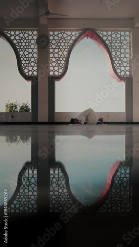 A Muslim man performing Islamic pray inside a mosque during Ramadan, a peaceful spiritual moment with beautiful mosque architecture and reflection on the polished floor.