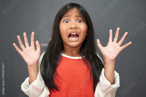 Quadro su tela Hysterical little Asian girl crying and looking terrified, panicked child with f