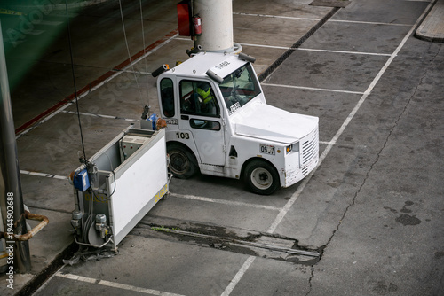 Airport ground tug vehicle parked on service lane near terminal used for aircraft towing a