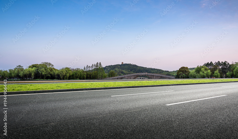 Fototapeta premium Scenic Road View with Lush Greenery and Distant Hills